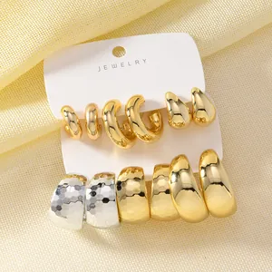 Detail showing various gold and silver C-shaped and drop earring styles on a card.