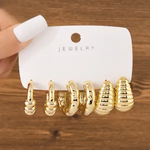 Detailed view of three pairs of chunky gold-toned hoop and drop earrings set