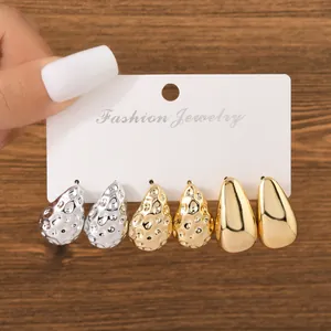 Macro view of three-piece teardrop earring set featuring gold and silver hammered textures.