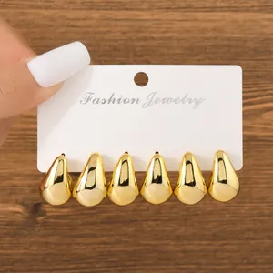 Detailed view of three pairs of shiny gold waterdrop earrings on a white display card