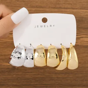 Close-up of mixed texture C-shaped hoop earrings in gold and silver finishes.
