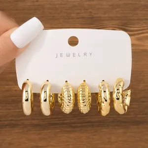 Detailed view of three pairs of gold-tone chunky C-shaped hoop earrings on display.