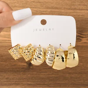 Close-up of three pairs of chunky golden earrings with textured and twisted patterns
