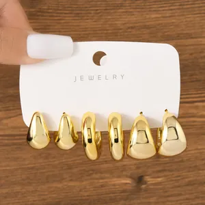 Detailed view of three pairs of chunky gold-toned fashion earrings on a display card
