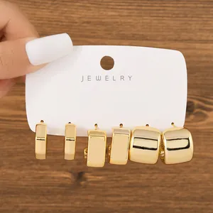 Detail of 3 pairs gold chunky C-shaped hoop earrings set on jewelry card display.
