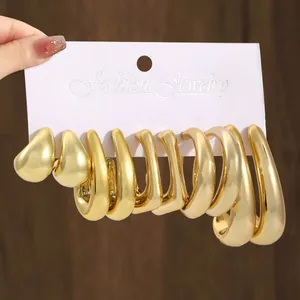 Close-up detail of a shiny gold-tone C-shape and teardrop earring set on display card