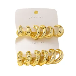 Exaggerated gold C-shaped twist and teardrop hoop earring set on white jewelry card for women