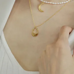 Vista dettagliata di una collana minimalista in oro con pendente irregolare al collo.