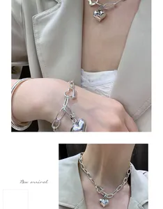 Detailed view of sterling silver chunky chain necklace with heart pendant on model.