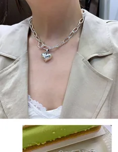 Detailed close-up of a chunky sterling silver heart pendant necklace worn by a model