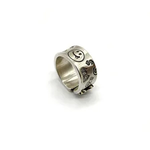 Close-up of retro sterling silver ring featuring engraved smiley face and dollar sign icons