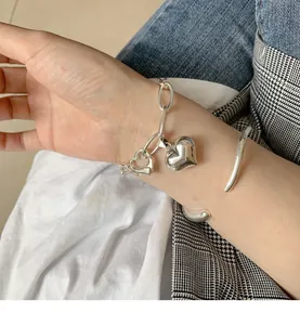 Detailed view of chunky 925 sterling silver heart bracelet and bangle on wrist.