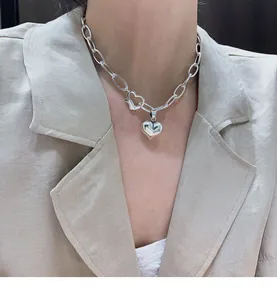 Close-up of 925 sterling silver heart pendant necklace on model with beige blazer