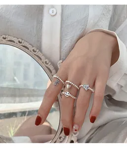 Detailansicht einer Hand mit einem eleganten Set aus silbernen Perlenringen mit Charms.