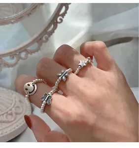 Detailansicht von Sterlingsilber-Perlenringen mit Schmetterlings- und Smiley-Anhängern