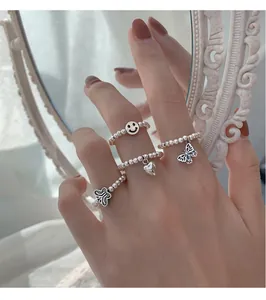Nahaufnahme einer Hand mit 925er Sterlingsilber-Perlenringen mit Schmetterling und Herz