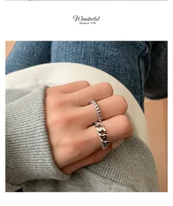 Detailed view of vintage distressed silver braided and Cuban link rings worn on a hand.