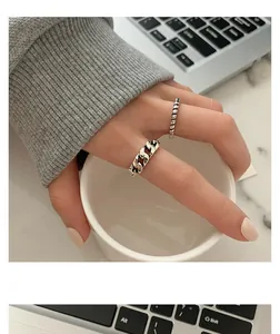 Detailed view of retro distressed twisted and hollow chain rings on model's hand
