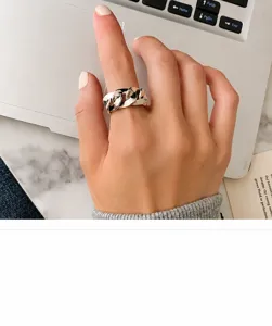 Detail showing the polished finish of a chunky silver curb link ring on a hand.