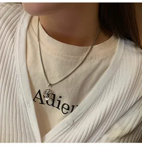 Close-up van een vintage zilveren engel hanger ketting gedragen met een wit vest