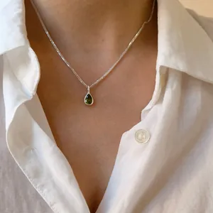 Close-up of green agate teardrop pendant on a 925 sterling silver chain worn on neck.