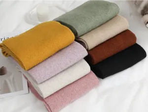 Detailweergave van diverse zachte, effen wintersjaals in warme herfstkleuren.