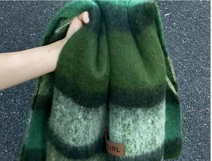 Detailed macro view of luxury green striped mohair scarf texture with leather tag