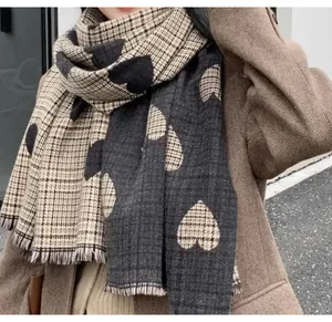 Close-up of a warm winter scarf featuring a heart and plaid pattern with fringed edges.