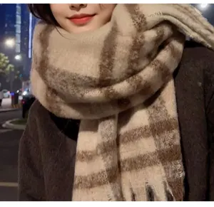 Detailed close-up of a soft plaid mohair scarf with tassels for winter warmth.