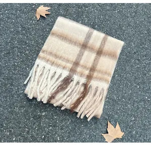 Detailed macro view of a soft mohair plaid scarf with tassels and autumn leaves