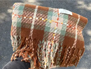 Macro detail of a soft autumn plaid scarf with tassels and brand woven label tag