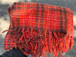 Close-up detail showing the soft texture and fringe of the red and orange plaid scarf
