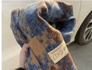 Close-up of blue and brown knitted plaid scarf with brand label texture details.