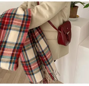Detailed shot of a cozy plaid scarf styled with a beige winter coat and red bag