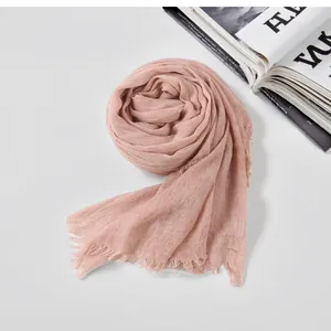 Detailed texture of a soft nude pink cotton linen scarf with wrinkled design and raw edges