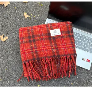 Detailed close-up of a warm red plaid faux cashmere scarf with fringe tassels for winter.