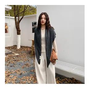 Detailed view of an Asian model wearing a dark grey knitted triangle shawl outdoors