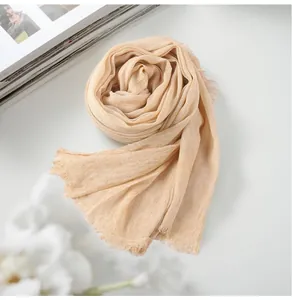 Close-up macro detail of apricot cotton linen scarf showing crinkle texture and fringe edge