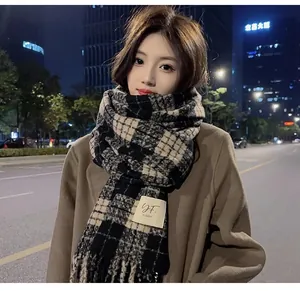 Close-up view of a warm black and tan checkered scarf styled with a brown wool coat