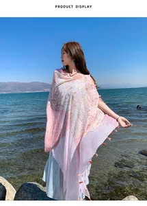 Ethnic style sun protection shawl with tassels shown in a scenic beach setting