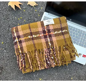 Detailed view of yellow plaid cashmere-like scarf with fringe tassels and brand tag