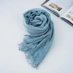Close-up detail of a light blue pleated cotton linen scarf showing soft natural texture