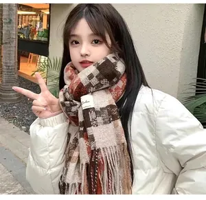 Detailed view of a stylish brown and orange plaid scarf with fringe worn by a young woman