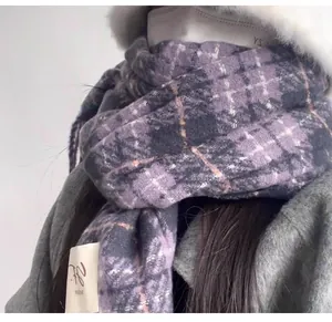 Detail of a purple plaid faux cashmere scarf worn with a gray coat for winter