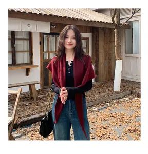 Elegant burgundy knit triangular shawl worn as a stylish autumn outdoor layering piece.