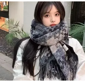 Close-up of cozy plaid tassel scarf on model