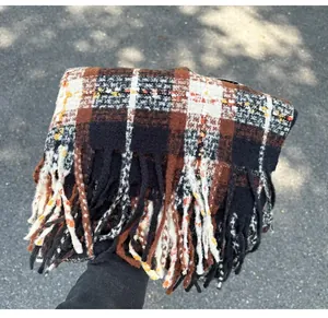 Detailed view of thick plaid winter scarf featuring long tassels and soft knit texture