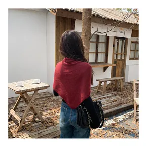 Red knitted triangle shawl wrap styled over a black top in a natural outdoor setting
