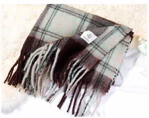 Detailed macro view of a thick Maillard plaid scarf with fringe tassels and brand label