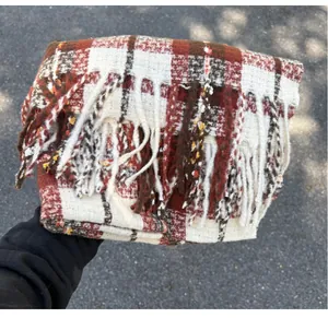 Close-up of a folded red and white plaid scarf with soft fringes and woven texture